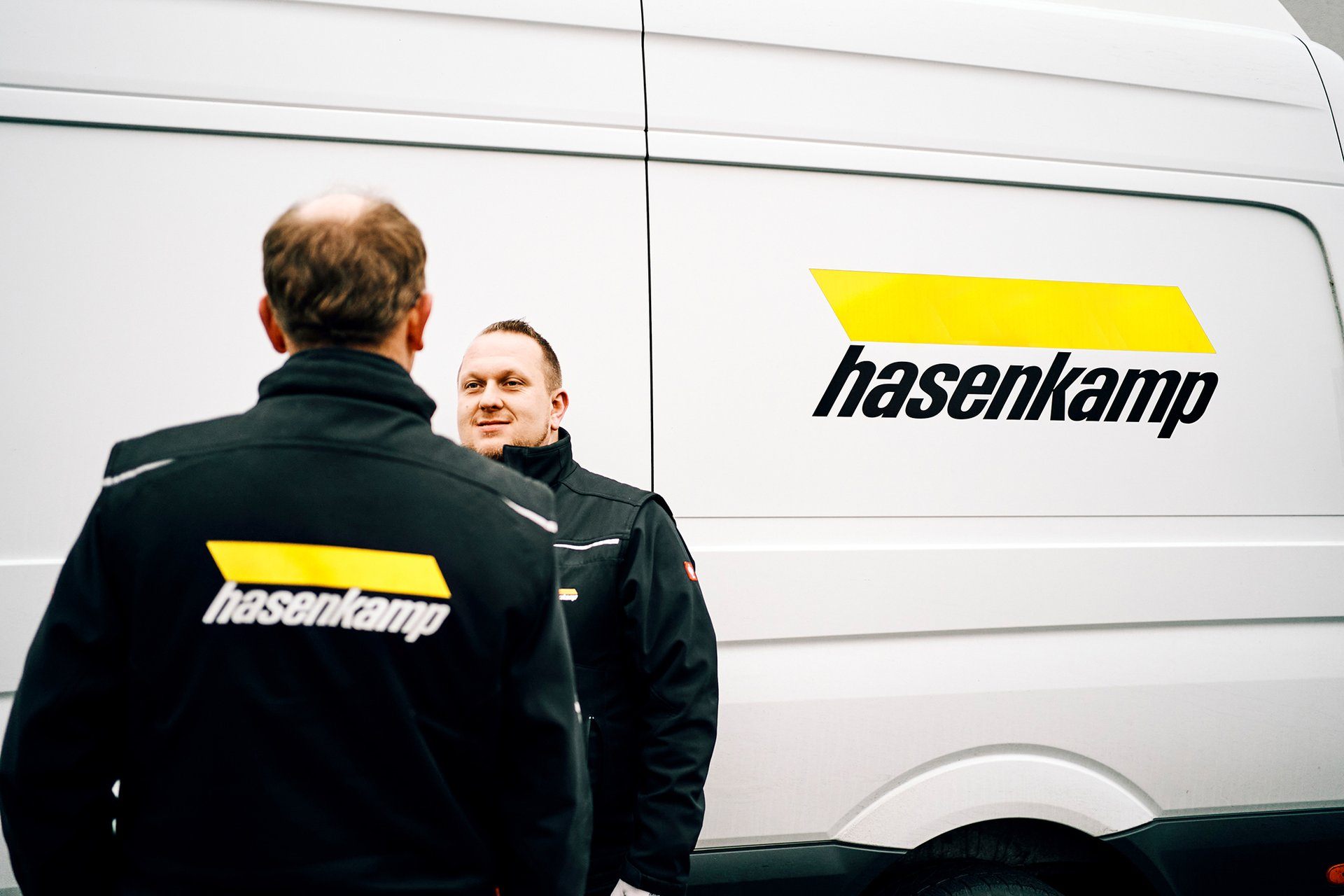 Zwei hasenkamp Mitarbeiter unterhalten sich vor einem Transporter.