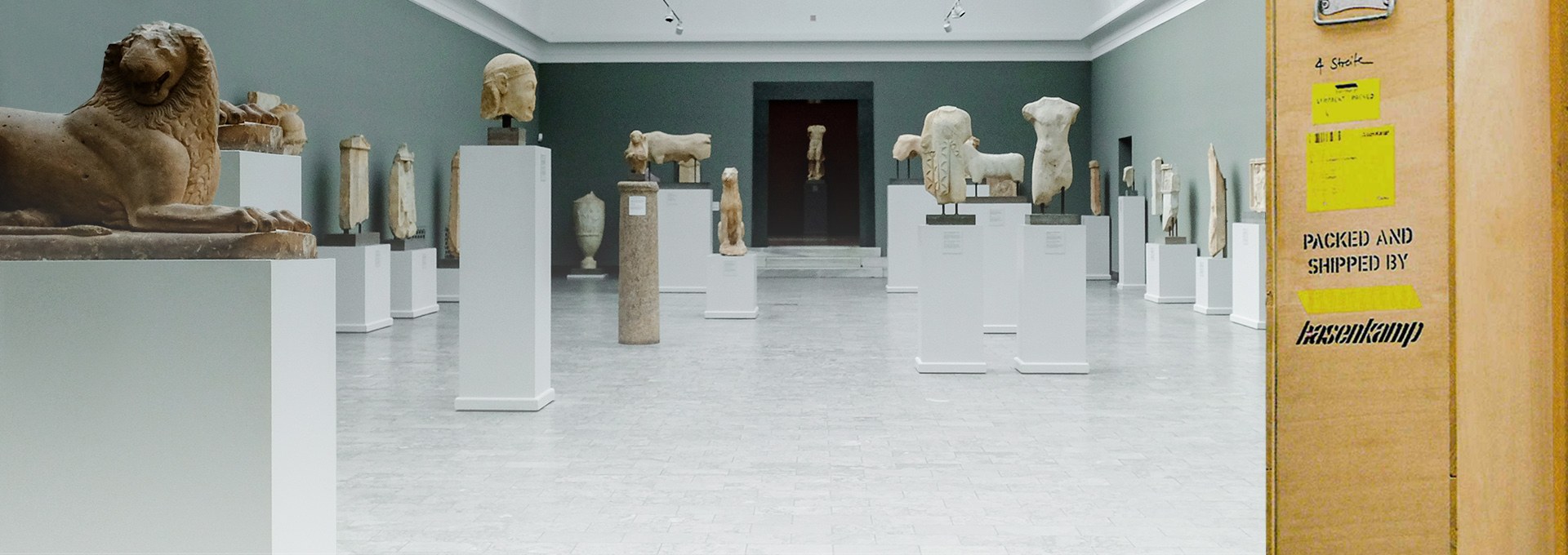 Ein Museums-Raum mit vielen Kunstwerken und einer Transportbox aus Holz mit hasenkamp Aufdruck.