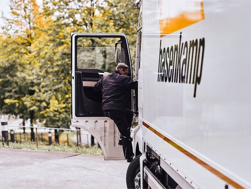 Ein Fahrer von hasenkamp steigt in das Fahrerhaus seines LKW ein.