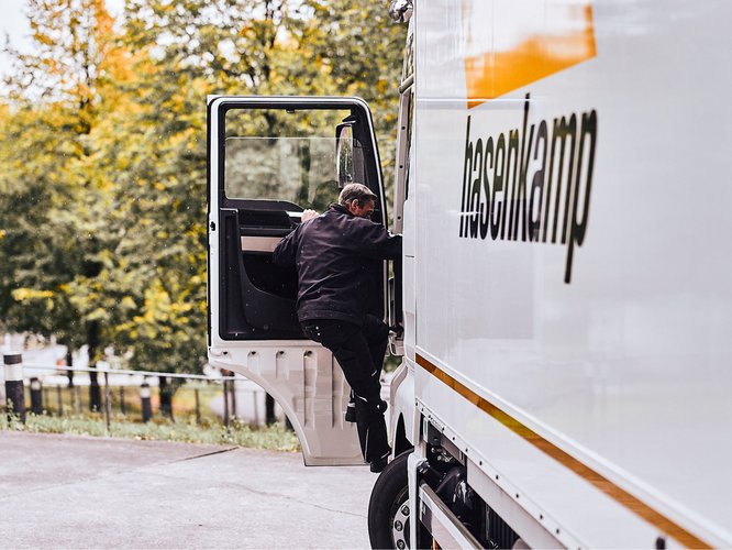 Ein Fahrer von hasenkamp steigt in das Fahrerhaus seines LKW ein.
