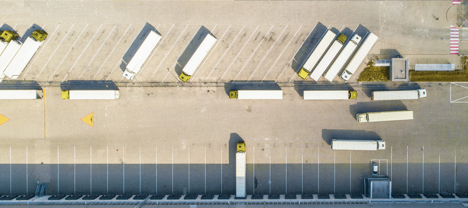 Mehrere Logistik-LKW stehen auf einem großen Parkplatz zur Abfahrt bereit.
